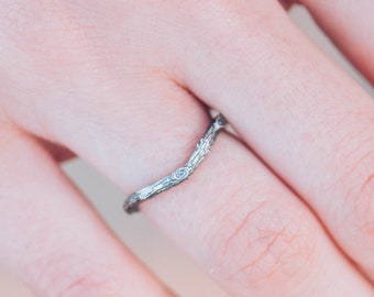 May include: A silver wedding band with a unique, organic design resembling a branch with small diamonds embedded in the metal.