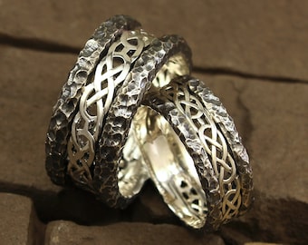 May include: Two silver wedding bands with a Celtic knot design. The bands are textured and have a hammered finish.