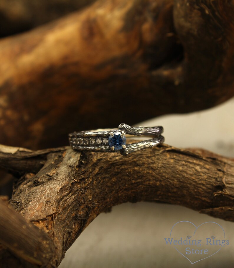 May include: A silver engagement ring with a blue gemstone and small diamonds set in a branch-like design.