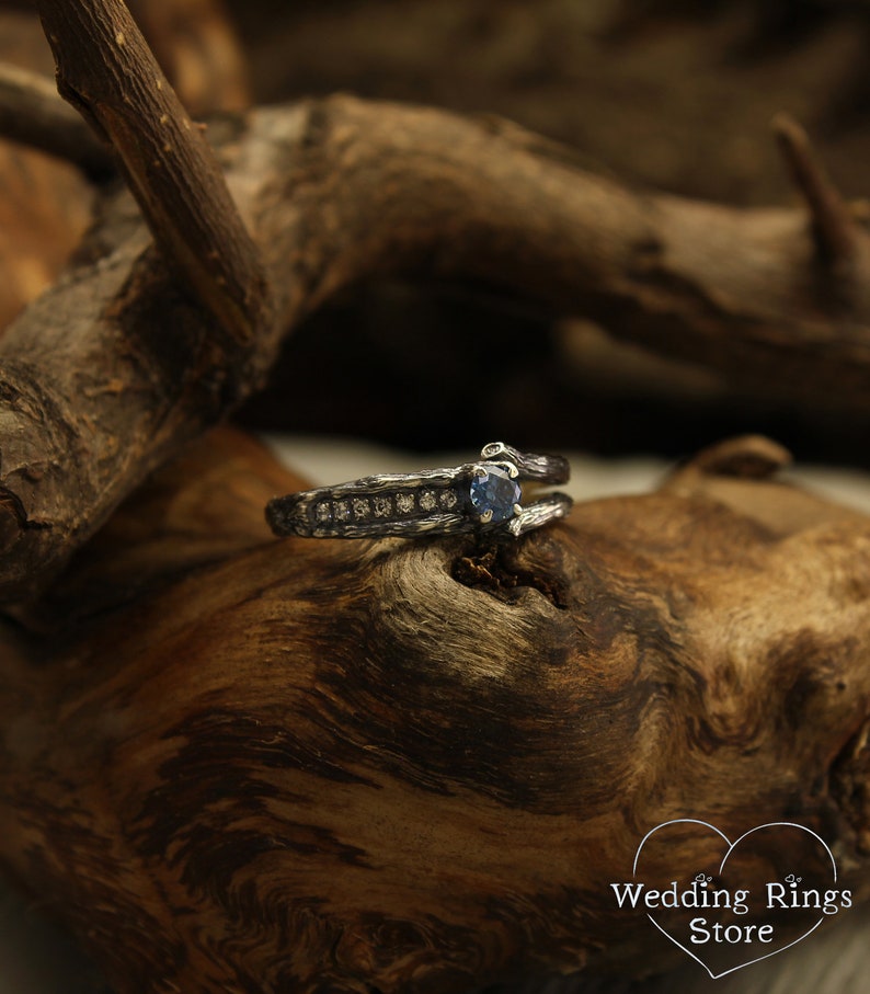 May include: A silver ring with a blue gemstone and small diamonds set in a textured band. The ring is on a piece of wood.