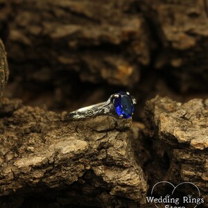 May include: A silver ring with a blue oval-shaped gemstone set in a floral design.