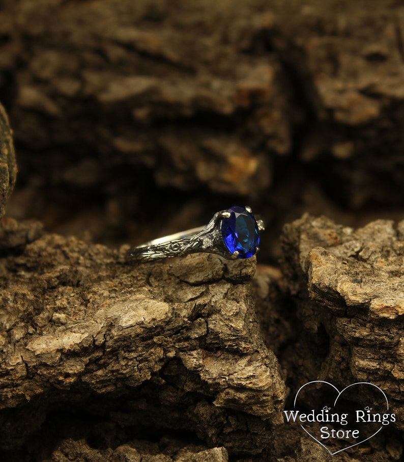 May include: A silver ring with a blue oval-shaped gemstone set in a floral design.