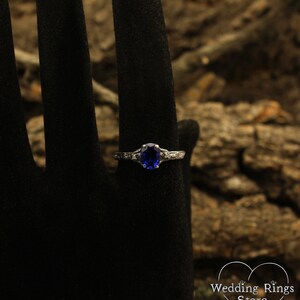 May include: A silver ring with a blue oval gemstone and small clear gemstones on the band.
