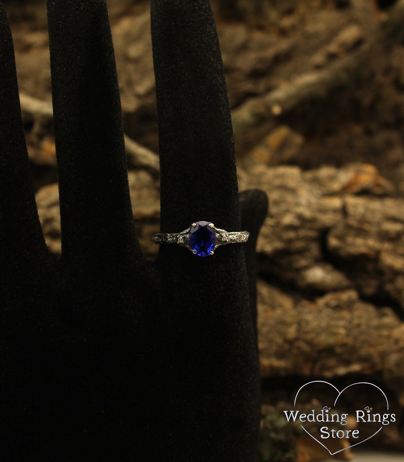 May include: A silver ring with a blue oval gemstone and small clear gemstones on the band.