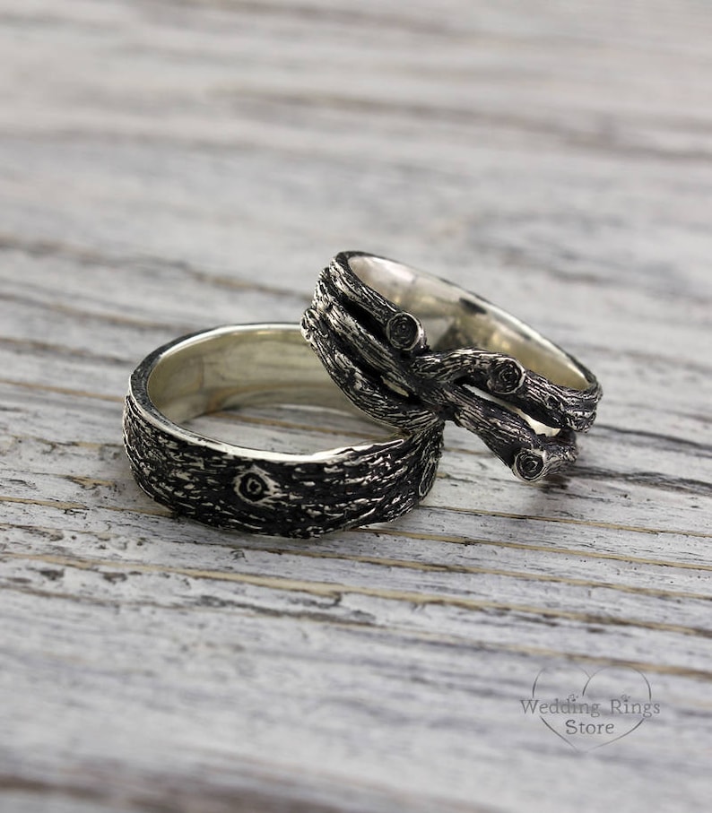 May include: Two silver wedding bands with a tree bark design. One band features a twisted branch design with black accents.
