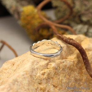 May include: A silver ring with a unique, intricate design. The ring is made of a smooth, polished metal and has a delicate, feminine look.