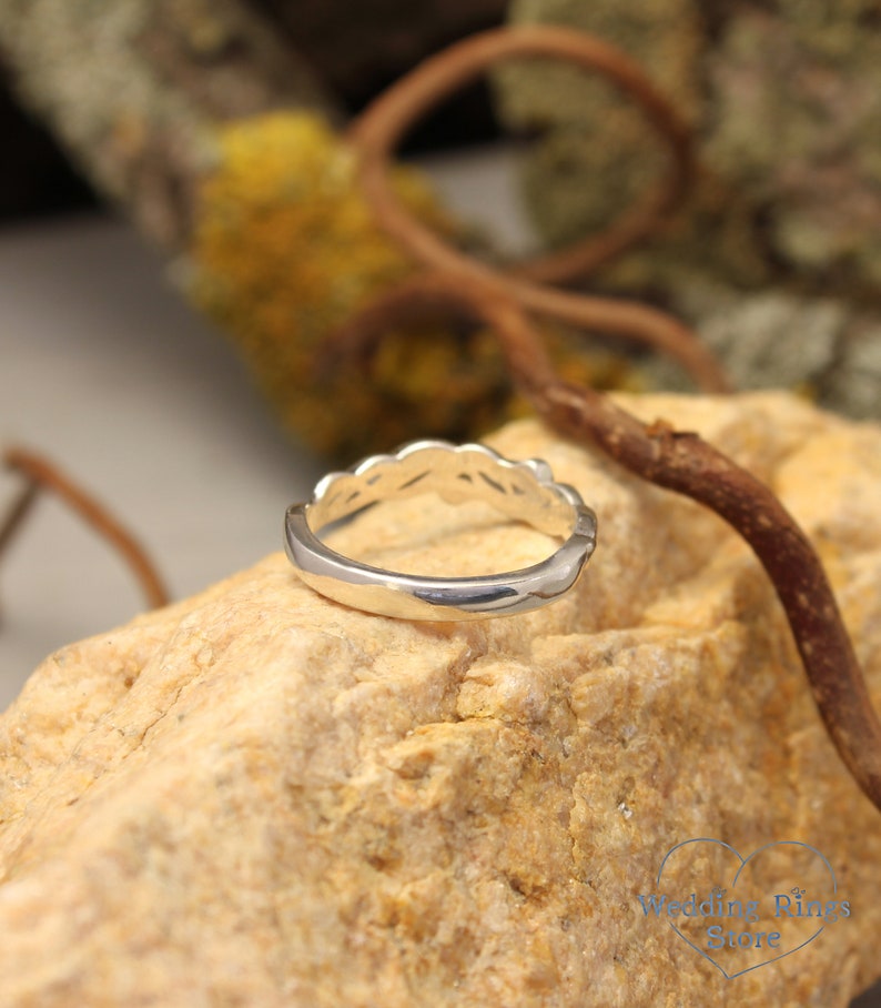 May include: A silver ring with a unique, intricate design. The ring is made of a smooth, polished metal and has a delicate, feminine look.
