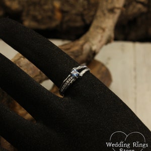 May include: A silver ring with a blue gemstone and small diamonds set in a twig-like band.