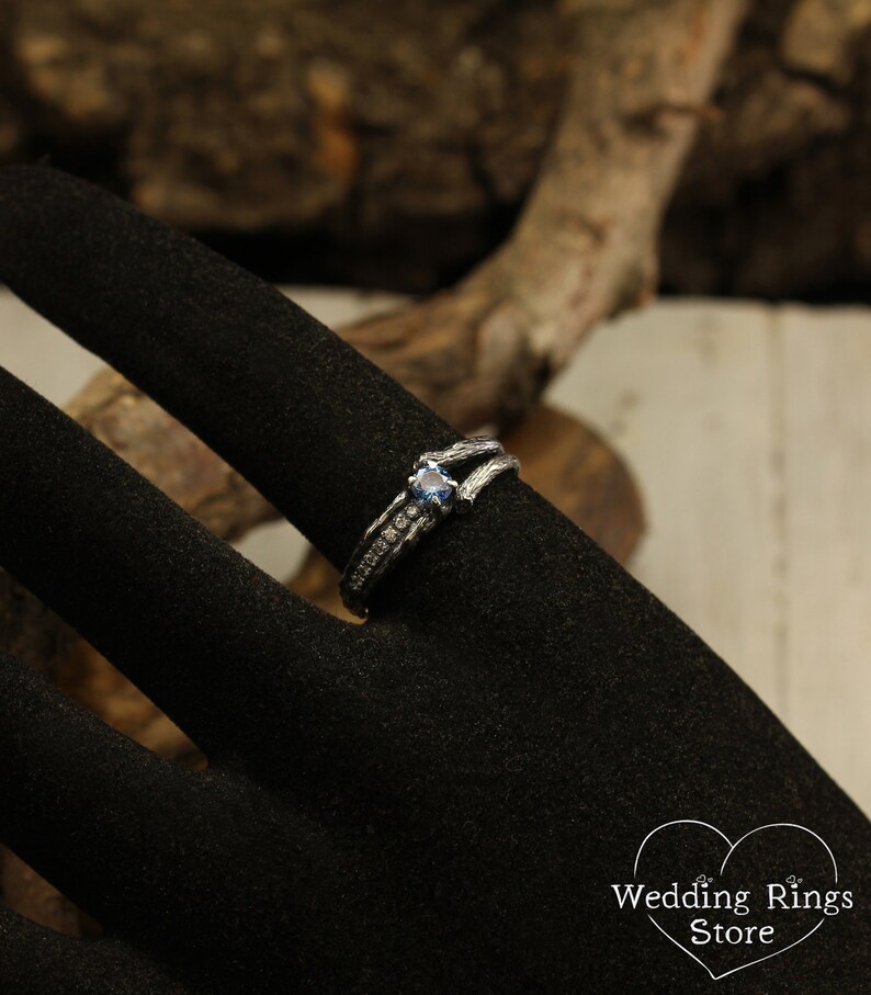 May include: A silver ring with a blue gemstone and small diamonds set in a twig-like band.