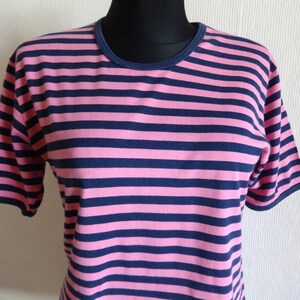 K&ouml;nnte beinhalten: Ein kurz&auml;rmeliges T-Shirt mit pinkfarbenen und dunkelblauen Streifen.