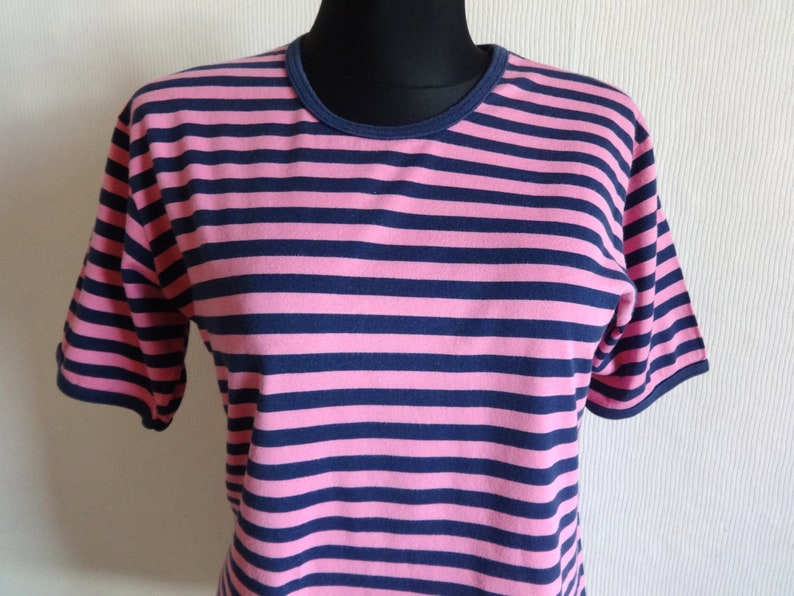 K&ouml;nnte beinhalten: Ein kurz&auml;rmeliges T-Shirt mit pinkfarbenen und dunkelblauen Streifen.