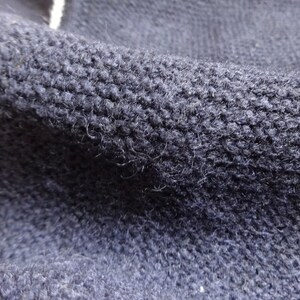 Puede incluir: Primer plano de una tela de punto azul oscuro con una superficie texturizada.
