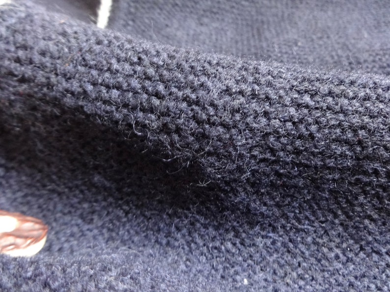 Puede incluir: Primer plano de una tela de punto azul oscuro con una superficie texturizada.