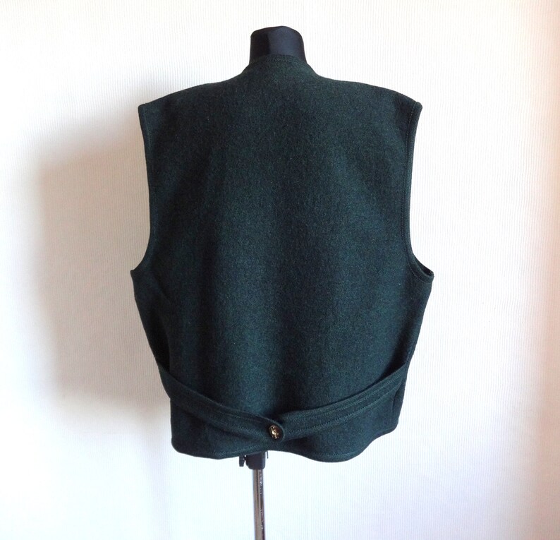 Puede incluir: Un chaleco de lana verde oscuro con cierre de bot&oacute;n y cintur&oacute;n en la espalda.