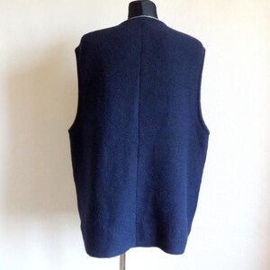 Puede incluir: Un chaleco de punto azul oscuro sin mangas con un ribete blanco alrededor del cuello.