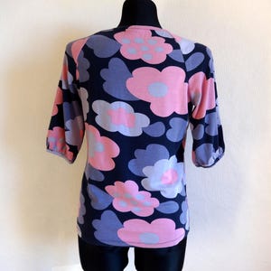 May include: A blue and pink floral print short-sleeved shirt with a round neckline.
