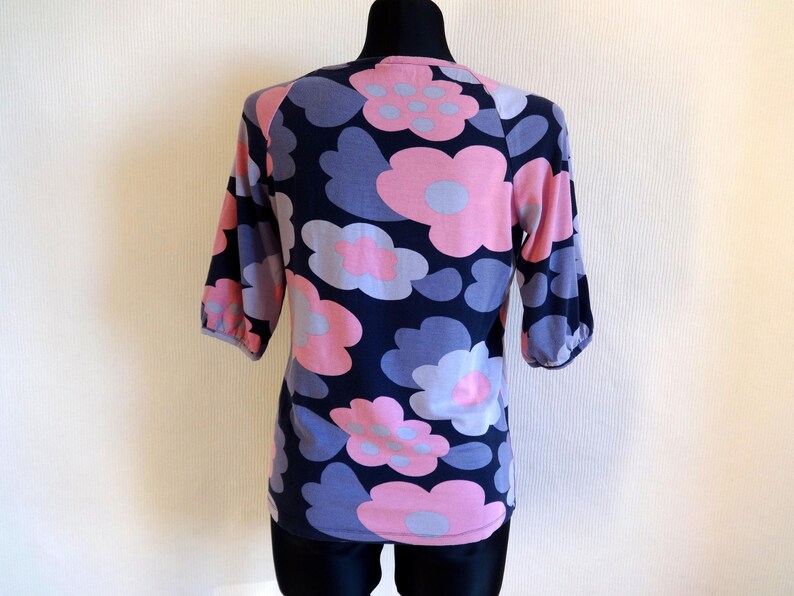 May include: A blue and pink floral print short-sleeved shirt with a round neckline.