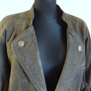 Puede incluir: Una chaqueta de cuero marr&oacute;n con cuello alto y dos botones plateados. La chaqueta tiene un aspecto desgastado y est&aacute; hecha de cuero suave y flexible.