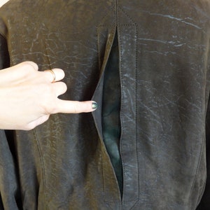 Puede incluir: Una chaqueta de cuero marr&oacute;n con una cremallera larga en la espalda. La cremallera est&aacute; abierta y el forro es visible.