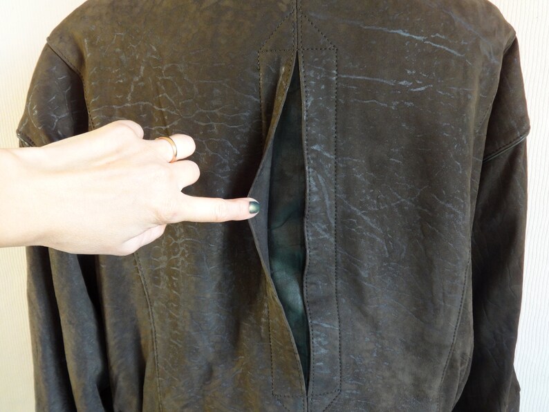 Puede incluir: Una chaqueta de cuero marr&oacute;n con una cremallera larga en la espalda. La cremallera est&aacute; abierta y el forro es visible.