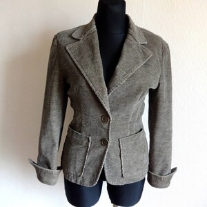 Op de afbeelding: Een grijze corduroy blazer met twee zakken en twee knopen. De blazer heeft een reverskraag en lange mouwen.
