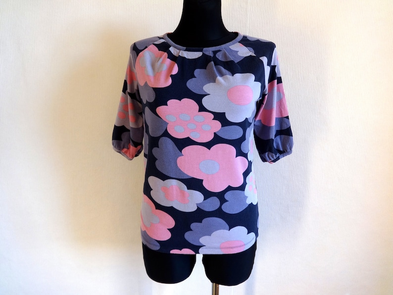 May include: A navy blue short-sleeved shirt with a pink and gray floral pattern.