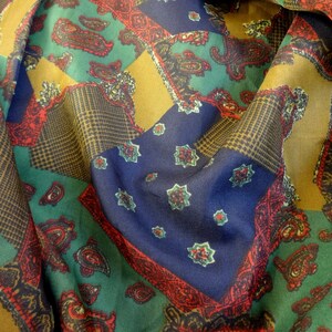 Puede incluir: Una tela colorida con un patr&oacute;n de paisley en tonos de verde, azul, rojo y dorado. La tela est&aacute; doblada y drapeada, mostrando los diferentes patrones y colores.