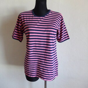 K&ouml;nnte beinhalten: Ein pinkfarbenes und marineblaues gestreiftes T-Shirt mit kurzen &Auml;rmeln und einem Rundhalsausschnitt.