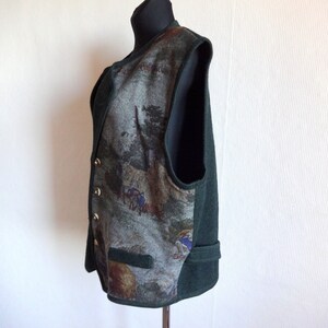 Puede incluir: Un chaleco verde sin mangas con un frente estampado que representa una escena de bosque. El chaleco tiene cierre de botones y un bolsillo en la parte delantera.