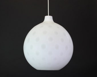 May include: A white, round, hanging light fixture with a textured surface. The light fixture has a small opening at the top for the cord.
