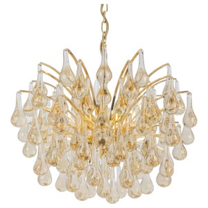 Könnte beinhalten: Ein goldener Kronleuchter mit einem kaskadierenden Design aus tropfenförmigen Glaskristallen. Die Kristalle sind eine Mischung aus Klarglas und Bernstein.