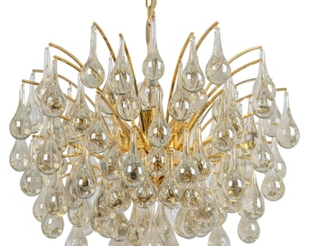 May include: A gold chandelier with many clear glass teardrop-shaped pendants.