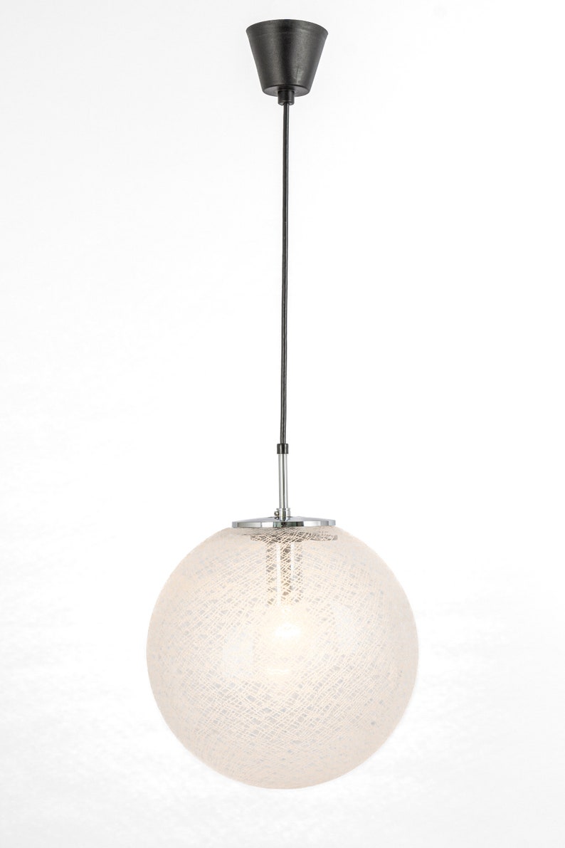 Peut inclure: Un luminaire suspendu en forme de globe blanc avec un cordon noir et une fixation au plafond chrom&eacute;e. Le globe pr&eacute;sente un motif d&eacute;licat et textur&eacute;.
