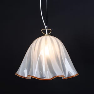 May include: A white glass pendant light with a ruffled, wavy design. The light has a gold metal ring at the top and a white cord.