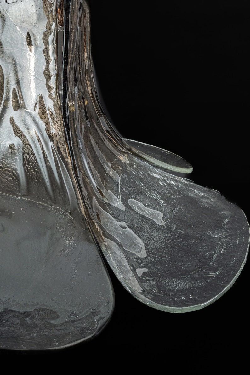May include: A clear glass vase with a unique, textured design. The vase has a wide, flared opening and a narrow base.