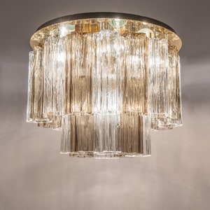 May include: A gold-toned ceiling light fixture with clear glass rectangular prisms hanging in tiers.