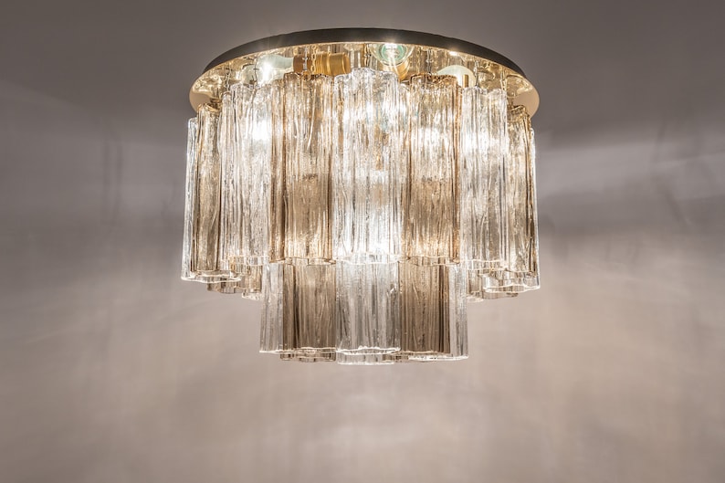 May include: A gold-toned ceiling light fixture with clear glass rectangular prisms hanging in tiers.