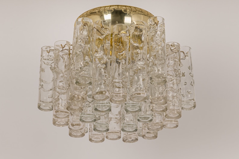 May include: A gold-toned ceiling light fixture with clear glass cylinders. The cylinders have a textured, bubbled surface.