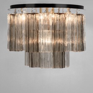 May include: A tiered chandelier with a black metal frame and clear glass rods. The chandelier has a modern design and is perfect for a contemporary home.