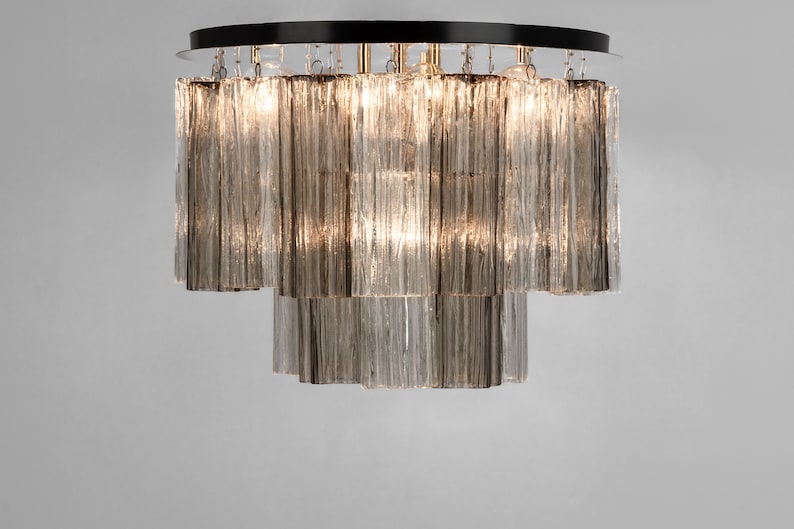 May include: A tiered chandelier with a black metal frame and clear glass rods. The chandelier has a modern design and is perfect for a contemporary home.