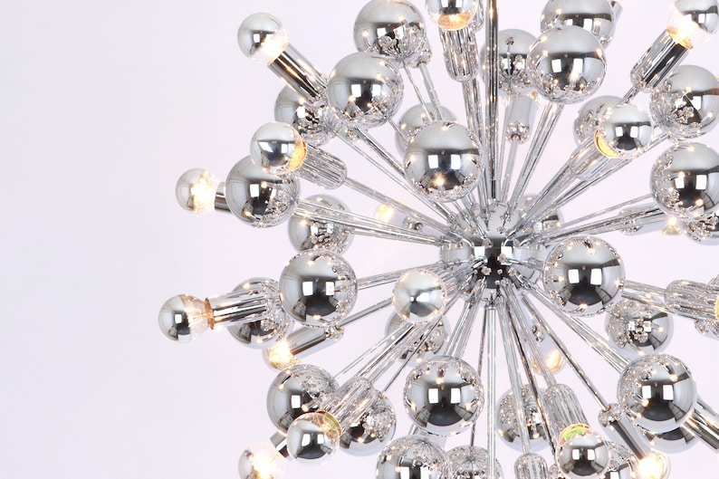 Op de afbeelding: Een chromen kroonluchter met meerdere ronde lampen, die een modern en geometrisch ontwerp cre&euml;ren.