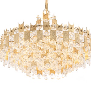 Peut inclure: Un lustre de couleur or avec un design g&eacute;om&eacute;trique et des accents de cristal transparent. Le lustre a une forme ronde et est suspendu &agrave; une cha&icirc;ne.