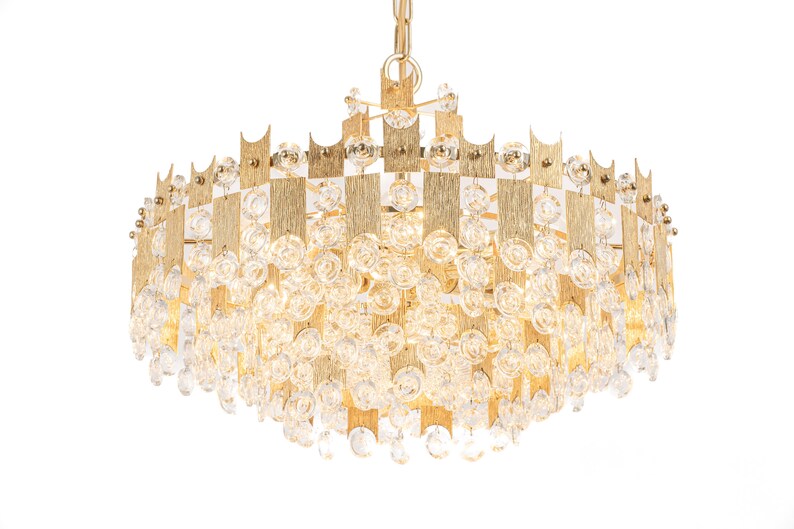 Peut inclure: Un lustre de couleur or avec un design g&eacute;om&eacute;trique et des accents de cristal transparent. Le lustre a une forme ronde et est suspendu &agrave; une cha&icirc;ne.