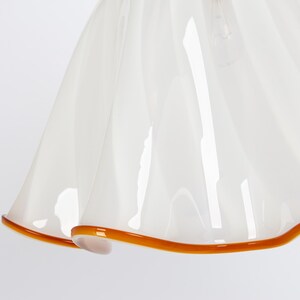 May include: White glass lampshade with a ruffled edge and a brown trim.