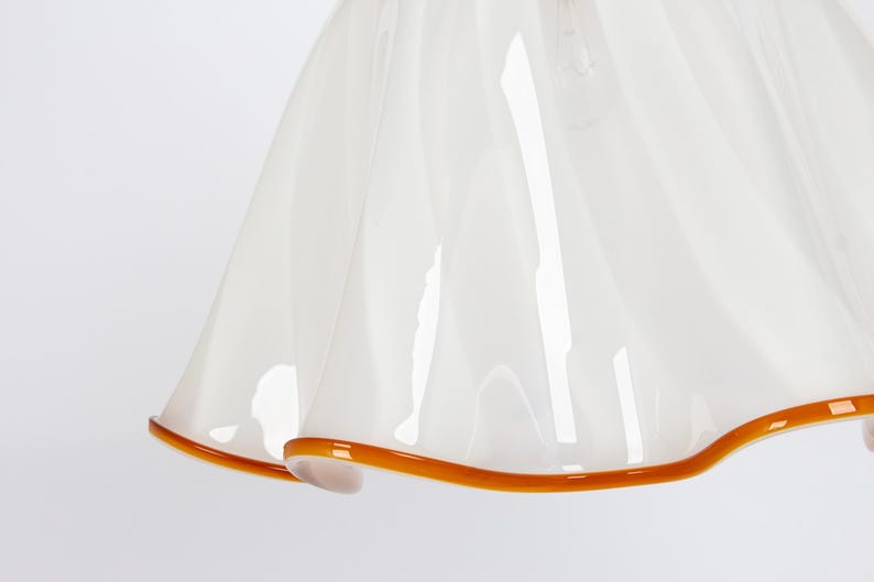 May include: White glass lampshade with a ruffled edge and a brown trim.