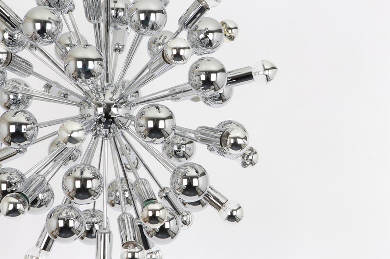 Op de afbeelding: Een chromen Sputnik-kroonluchter met meerdere ronde lampen die naar buiten uitstrekken vanaf een centraal punt.