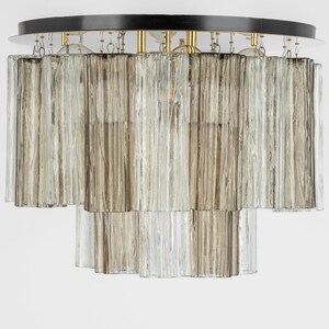 May include: A ceiling light fixture with a black circular base and multiple rows of clear and frosted glass tubes.