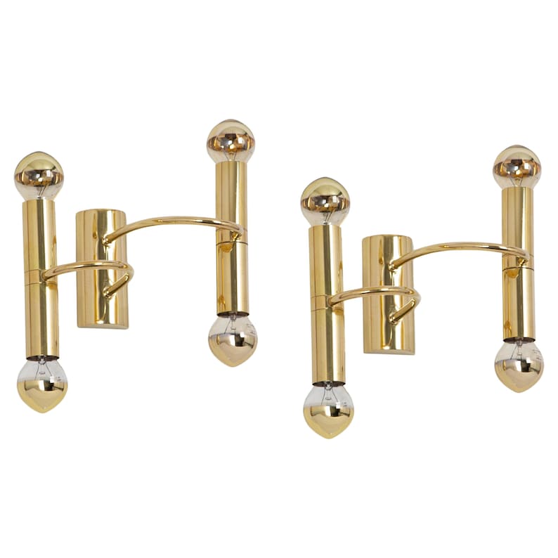 May include: Two gold-colored wall sconces with a minimalist design. Each sconce features a vertical tube with a bulb at the top and bottom, connected by a curved arm to a rectangular wall mount. The bulbs have a reflective, silver-gold finish.
