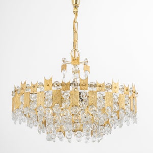Peut inclure: Un lustre de couleur or avec un design g&eacute;om&eacute;trique et des accents de cristal transparent. Le lustre a une forme circulaire et est suspendu &agrave; une cha&icirc;ne.