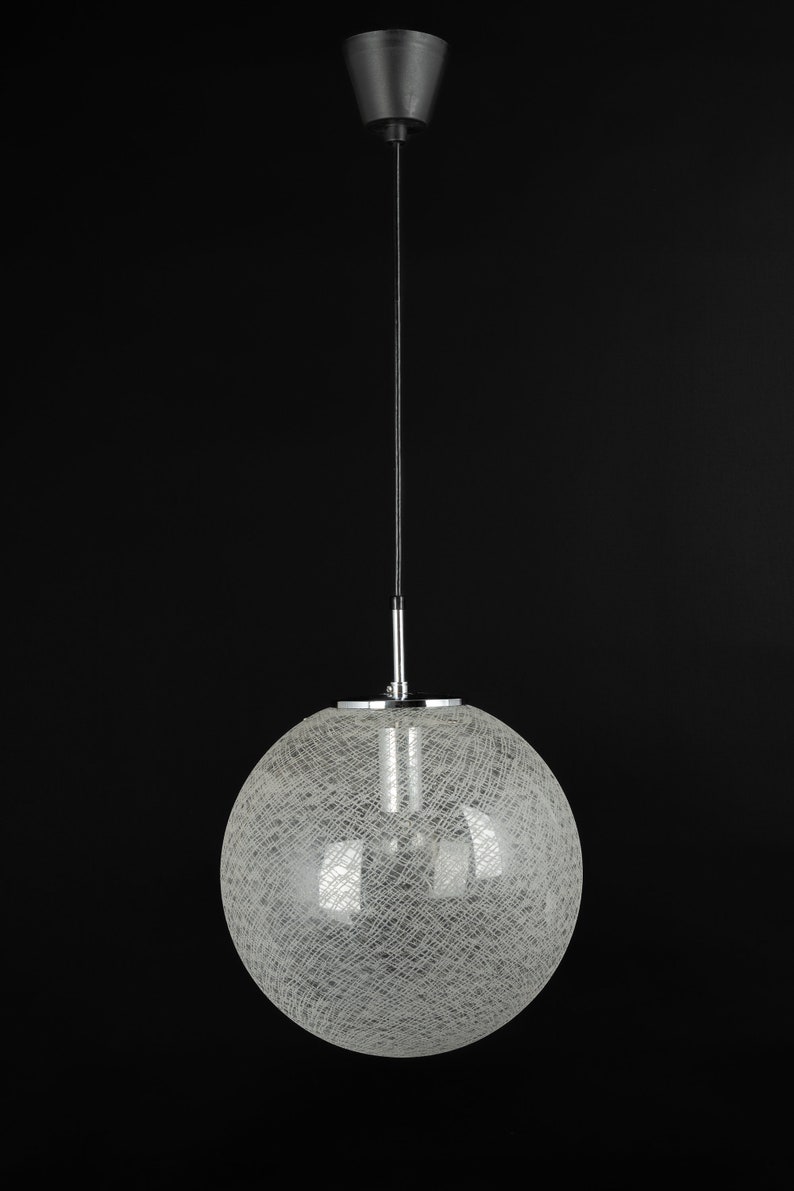 Peut inclure: Un luminaire suspendu rond en fil de fer blanc avec un cordon noir et une fixation au plafond noire.